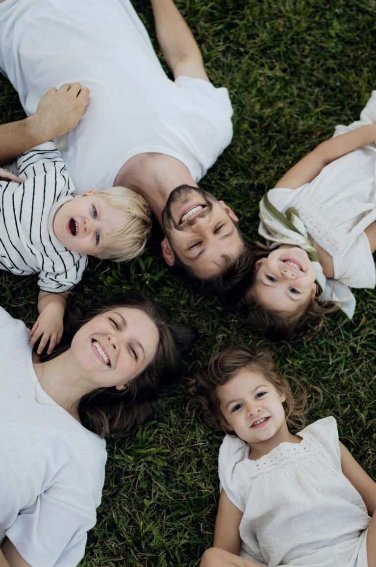 Familjefotograferi på familj liggandes på en gräsmatta.