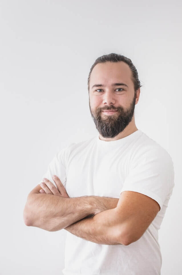 Man med armar i kors och ett leende under fotografering i studio.